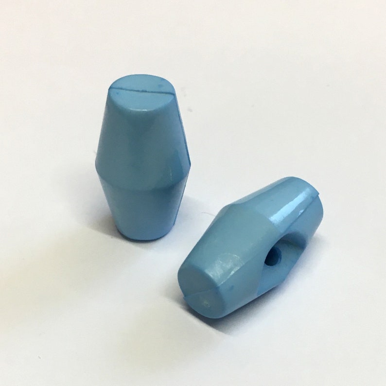 May include: Two light blue plastic toggles with a hole in one of them.