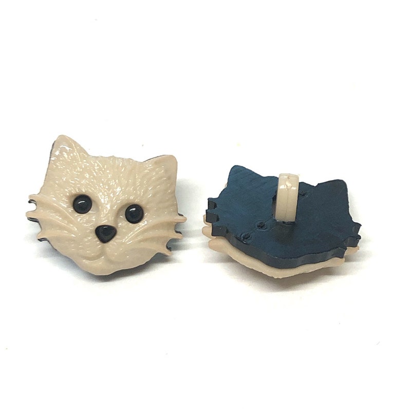 Pu&ograve; includere: Un paio di bottoni in plastica beige a forma di viso di gatto con occhi neri. Il retro del bottone &egrave; blu.