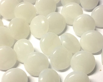 May include: A collection of white, round, smooth, opaque buttons. The buttons are arranged in a random pattern on a white surface.