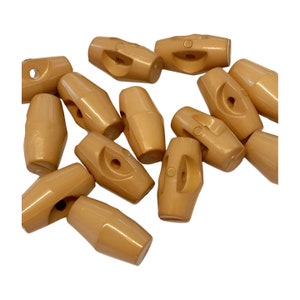 May include: A group of 12 brown plastic toggle buttons. The buttons are oval shaped with two holes in each button.