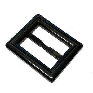 以下が含まれることがあります： 長方形で滑らかで光沢のある仕上げの黒いプラスチック製のバックルです。