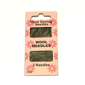 May include: A pink and white package of two hand sewing needles for wool. The package has a floral design and the text "Hand Sewing Needles", "Wool Needles", and "2 Needles".