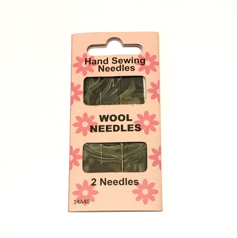 May include: A pink and white package of two hand sewing needles for wool. The package has a floral design and the text "Hand Sewing Needles", "Wool Needles", and "2 Needles".