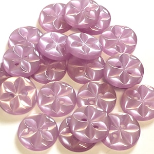 May include: A pile of 18 light purple plastic buttons with a flower design. Each button has two holes.