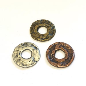 Puede incluir: Tres anillos de metal con textura martillada. Los anillos son de plata, oro y cobre.