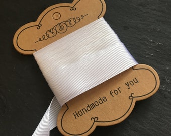 May include: A white satin ribbon wound around a brown cardboard tag with the text "Handmade for you".