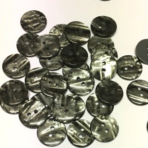 Puede incluir: Una colección de 20 botones redondos de dos agujeros con un patrón de remolinos en blanco y negro.