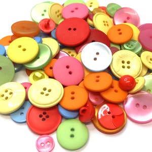 May include: A large collection of colourful plastic buttons in various sizes and shapes. The buttons are a mix of red, orange, yellow, green, blue, pink, and white.