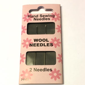 May include: A pink and white package of two hand sewing needles labeled "Wool Needles". The package has a pink floral design and the text "Hand Sewing Needles" and "2 Needles".