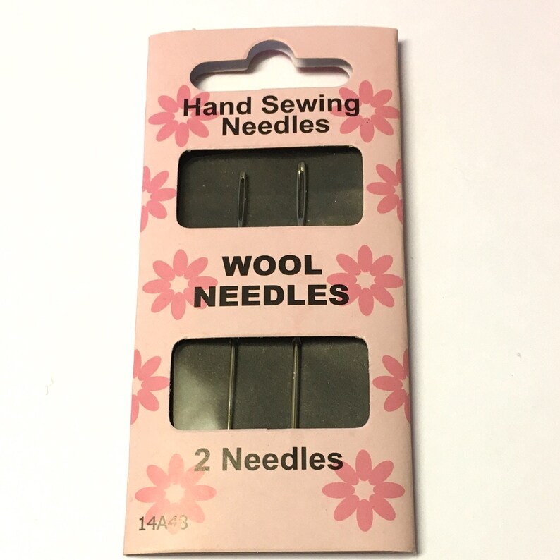 May include: A pink and white package of two hand sewing needles labeled "Wool Needles". The package has a pink floral design and the text "Hand Sewing Needles" and "2 Needles".
