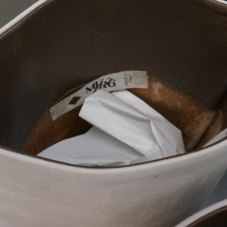 Puede incluir: Primer plano del interior de una bota de cuero blanco con forro marr&oacute;n. Una etiqueta blanca con el texto "M/R6 MADE IN ITALY" es visible dentro de la bota. La bota parece nueva, con papel blanco en su interior.