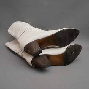 Puede incluir: Un par de botas de cuero blanco roto con tac&oacute;n medio. Las botas tienen un dise&ntilde;o ligeramente arrugado y una punta puntiaguda. Las suelas son de color marr&oacute;n oscuro y los tacones son de un tono m&aacute;s oscuro de marr&oacute;n. Talla 38.