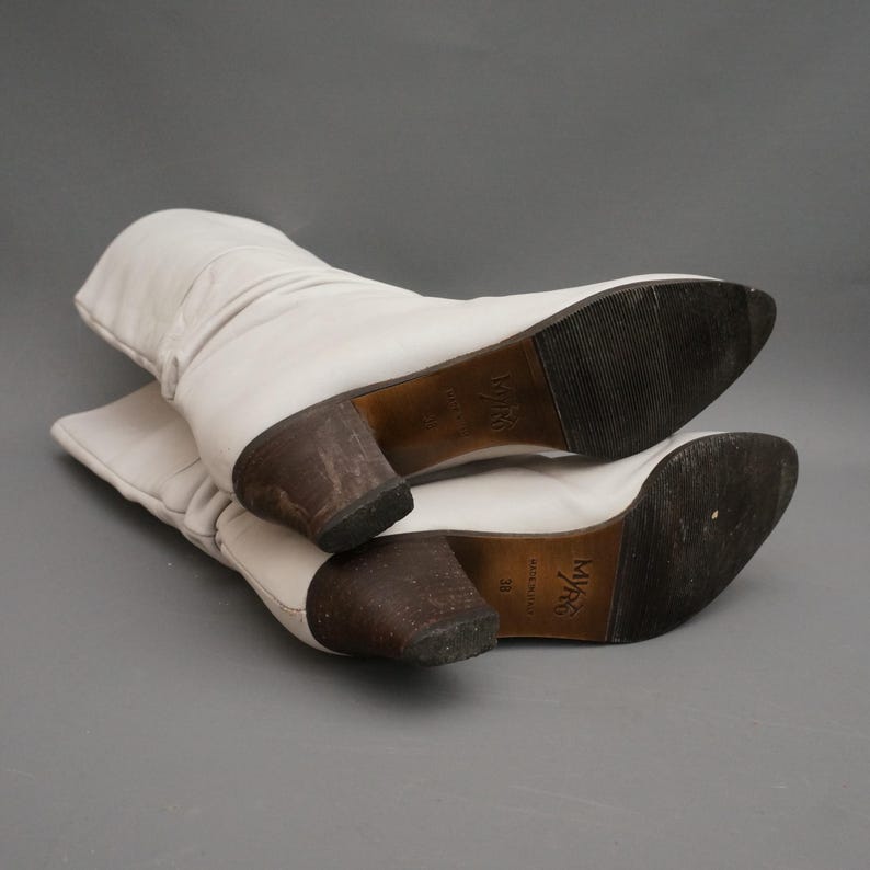 Puede incluir: Un par de botas de cuero blanco roto con tac&oacute;n medio. Las botas tienen un dise&ntilde;o ligeramente arrugado y una punta puntiaguda. Las suelas son de color marr&oacute;n oscuro y los tacones son de un tono m&aacute;s oscuro de marr&oacute;n. Talla 38.