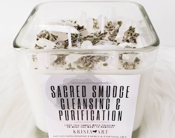 May include: A square glass candle jar with a white candle and a label that reads "Sacred Smudge Cleansing & Purification" with the text "Krista Art" below. The candle is topped with white crystals and dried herbs.