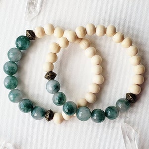 May include: Two bracelets, one with green jade beads and the other with natural wood beads, both with gold accents.