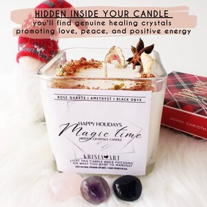 May include: A white candle with a label that reads "Happy Holidays Magic Time Hidden Crystals Candle". The candle is decorated with dried fruit, star anise, and rose petals. The label also lists the crystals included: Rose Quartz, Amethyst, and Black Onyx. The candle is sitting on a white surface with three crystals: a pink rose quartz, a purple amethyst, and a black onyx.