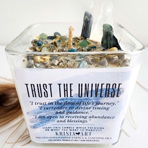 May include: A square glass jar candle with a white label that reads "TRUST THE UNIVERSE" and includes the text "I trust in the flow of life's journey." "I surrender to divine timing and guidance." "I am open to receiving abundance and blessings."  The label also includes the text "LIGHT THIS CANDLE WHILE FOCUSING ON WHAT YOU WANT TO MANIFEST" and "KRISIA ART". The candle is infused with positive energy and essential oils. It is made with 100% natural premium soy wax and hand-poured in the USA.