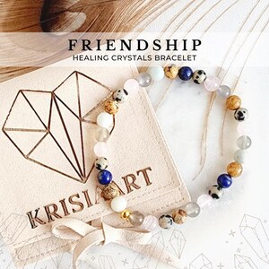 May include: A friendship bracelet made with healing crystals in a variety of colors, including pink, blue, brown, and white. The bracelet is packaged in a small, heart-shaped pouch with the words "Krisiart" printed on it. The pouch is made of a soft, suede-like material.