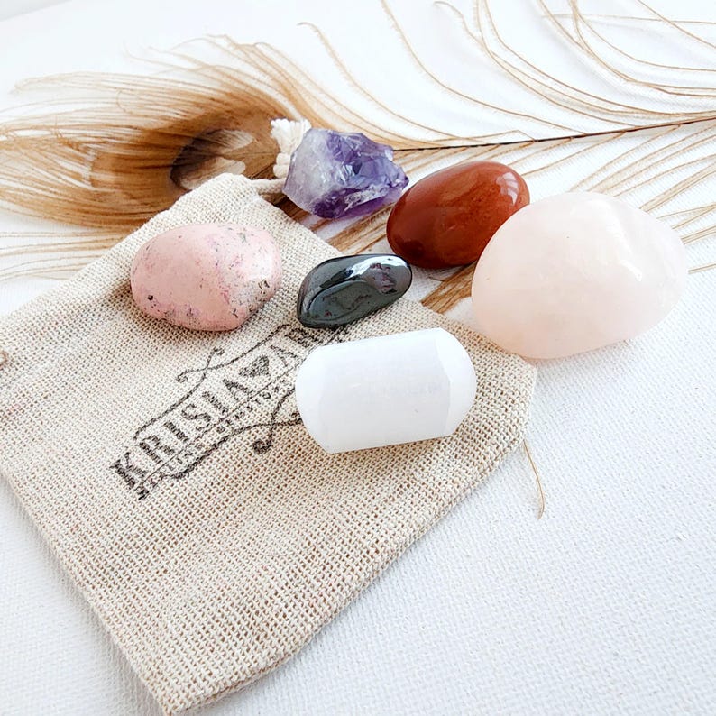 May include: A set of six tumbled stones in a small burlap bag. The stones are amethyst, red jasper, rose quartz, white selenite, and black hematite. The bag has the text "Krisia Za" printed on it.
