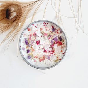 May include: A white candle with pink and purple crystals and gold glitter embedded in the wax.