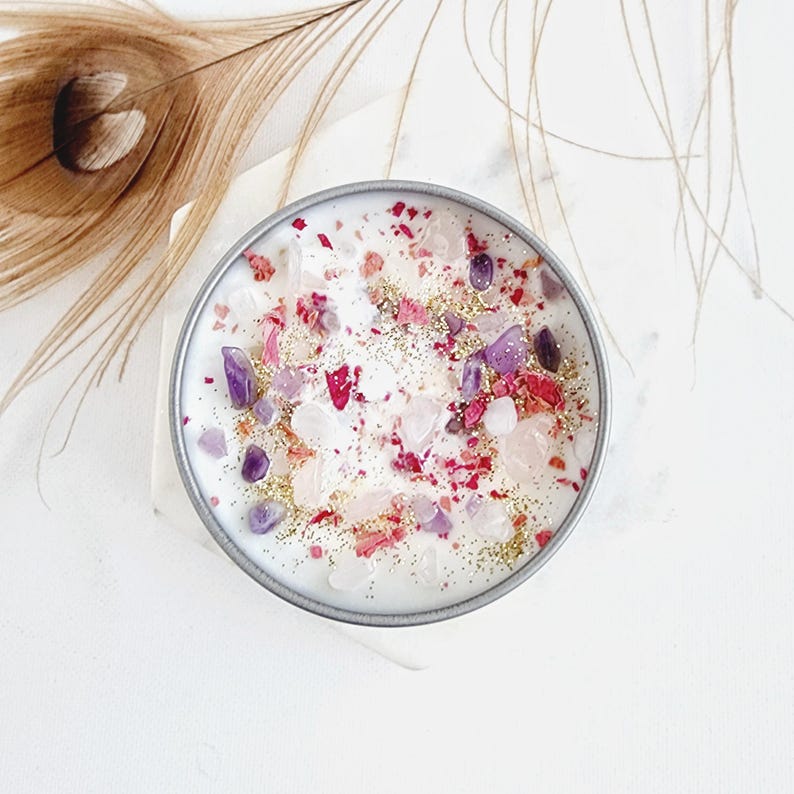 May include: A white candle with pink and purple crystals and gold glitter embedded in the wax.