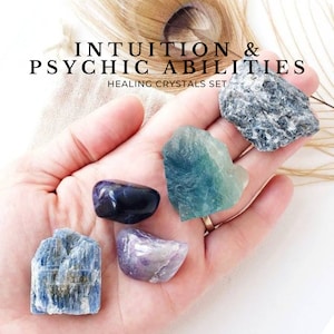 May include: A set of six healing crystals for intuition and psychic abilities. The crystals are blue, green, purple, and gray. The crystals are arranged in a hand.