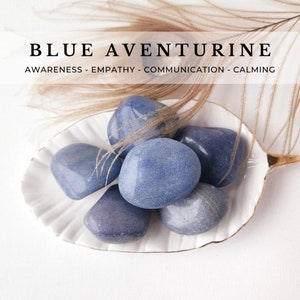 May include: A collection of smooth, blue aventurine stones in a white, scalloped dish. The stones are tumbled and have a slightly sparkly finish. The text "BLUE AVENTURINE" and "AWARENESS - EMPATHY - COMMUNICATION - CALMING" is displayed above the dish.