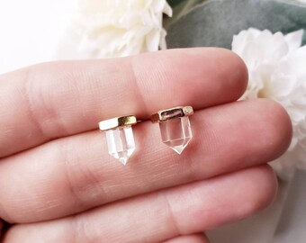 May include: A pair of gold-plated crystal point earrings. The earrings are small and delicate, and the crystal points are clear and faceted.