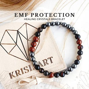 May include: A black, brown, and grey beaded bracelet with a hematite and red jasper stone design. The bracelet is in a small pouch with the text "KRISIART" on it. The text "EMF PROTECTION HEALING CRYSTALS BRACELET" is above the pouch.