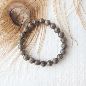 May include: A brown and gray beaded bracelet with a speckled pattern.