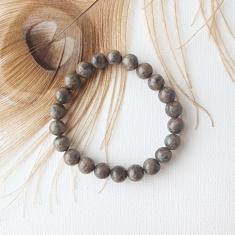 May include: A brown and gray beaded bracelet with a speckled pattern.