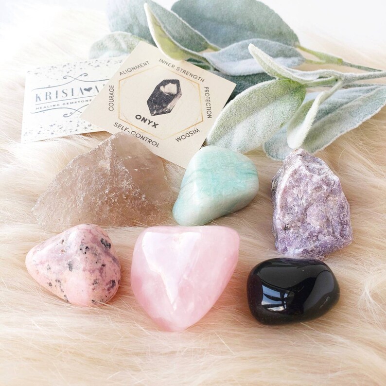 Puede incluir: Un conjunto de siete cristales pulidos, que incluyen cuarzo rosa, amatista, cuarzo transparente, aventurina verde, rodocrosita rosa y &oacute;nix negro. Cada cristal est&aacute; etiquetado con su nombre y propiedades asociadas en una peque&ntilde;a tarjeta.