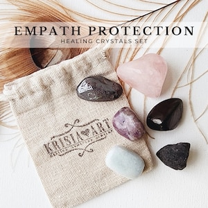 May include: A set of six tumbled crystals in a small, beige drawstring bag. The crystals are pink, purple, black, gray, and brown. The bag has the text "KRISTAL ART" printed on it. The crystals are labeled "Empath Protection Healing Crystals Set".