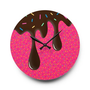 May include: A pink and brown round clock with a chocolate glaze design and colorful sprinkles. The clock hands are black.