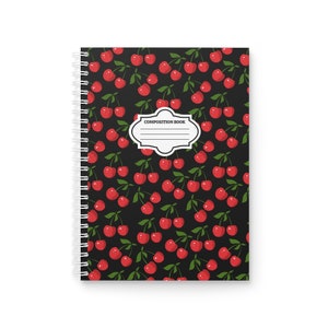 May include: A black composition book with a red cherry pattern and the text "COMPOSITION BOOK" on the front cover.