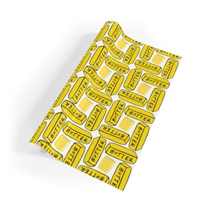 May include: White wrapping paper with a repeating pattern of yellow stick butter with the word "BUTTER" printed on each stick.