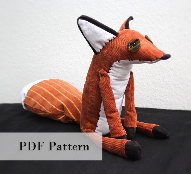 May include: A plush fox toy with a white belly, orange and brown striped tail, and brown corduroy body. The fox has black eyes and a button nose. The toy is sitting on a black surface. The text "PDF Pattern" is visible at the bottom of the image.