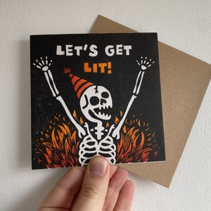 Tarjeta de felicitación de cumpleaños impresa a mano con esqueleto de fiesta. ¡Vamos a encendernos!