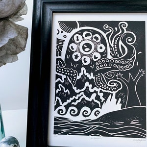 May include: Black and white linocut print of an octopus with a large eye, tentacles, and a whale in the water below. The print is titled "The Dreaming".