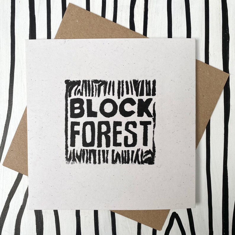 May include: A white card with black text that reads "BLOCK FOREST" in a blocky font. The text is surrounded by a black border made of small lines.