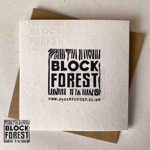 May include: Square white card with the words "BLOCK FOREST" in bold black letters. The card is on top of a brown envelope. The website address www.blockforest.co.uk is printed at the bottom of the card.