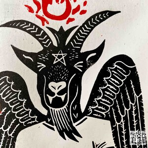 May include: Black and white illustration of a winged goat with a pentagram on its forehead. The goat is surrounded by a red flame.