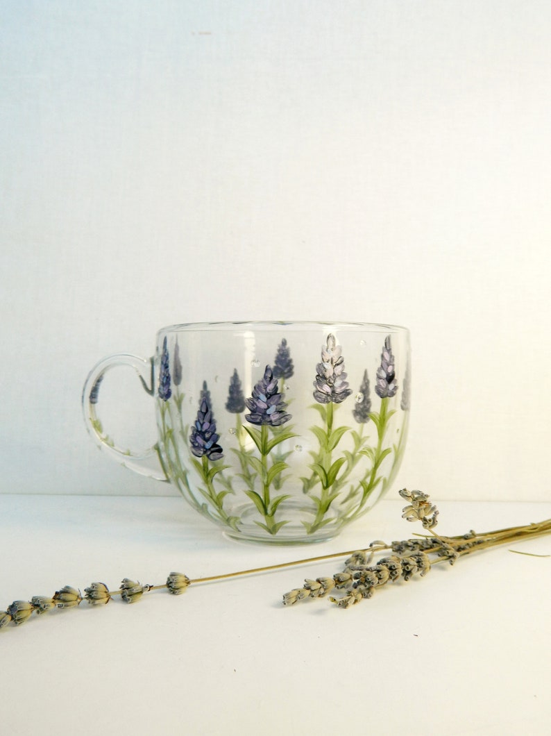Large round transparent glass mug with hand-painted Lavender.
Graceful lavender, with silvery-green foliage and spikes of purple flowers with pink and light blue smears. Lavender twigs of different heights. Transparent drops between flowers.