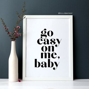 May include: White framed print with black text that reads "go easy on me, baby".