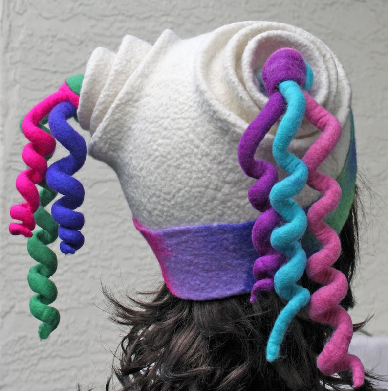 Puede incluir: Sombrero de fieltro blanco con un dise&ntilde;o escult&oacute;rico &uacute;nico. El sombrero presenta una serie de tiras de fieltro rizadas en rosa, verde, azul y morado.