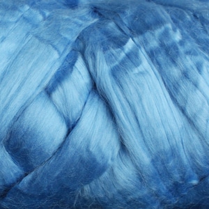 May include: Close-up of a blue, fluffy fiber, resembling a cloud-like texture. The fiber is soft and appears to be made of natural materials.