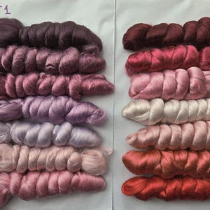 May include: Two sets of dyed silk fiber bundles in various shades of pink, purple, and red. The bundles are arranged in rows, with each row displaying a different color variation. The text "KIT1" and "KIT2" are written at the top of each set.