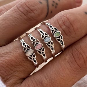 May include: A handmade wooden sign displaying the word "Welcome" in a whimsical font. The sign is painted white with a distressed effect, and adorned with a floral design in pink and green hues. It measures roughly 30 cm wide and 15 cm high.