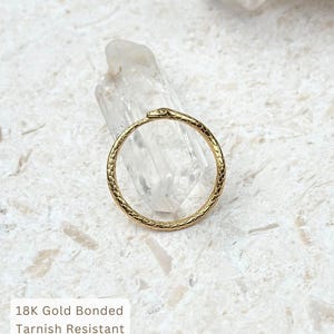 May include: A gold-colored ring with a snake design. The ring is circular with a textured pattern and a snake head at the top. The ring is on a white surface. Text on the image reads: 18K Gold Bonded, Tarnish Resistant, Hypoallergenic, Water Friendly.
