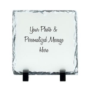 May include: A white slate plaque with a black inscription that reads "Your Photo & Personalized Message Here". The plaque has two black metal stands on the bottom.